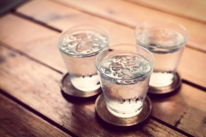 Drinking cold water into a  three glass placed on the wooden tab